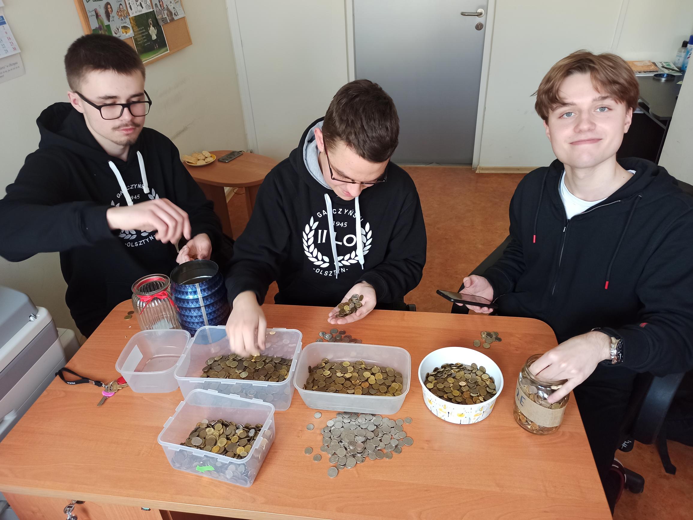 Uczniowie liczą monety zebrane w czasie akcji