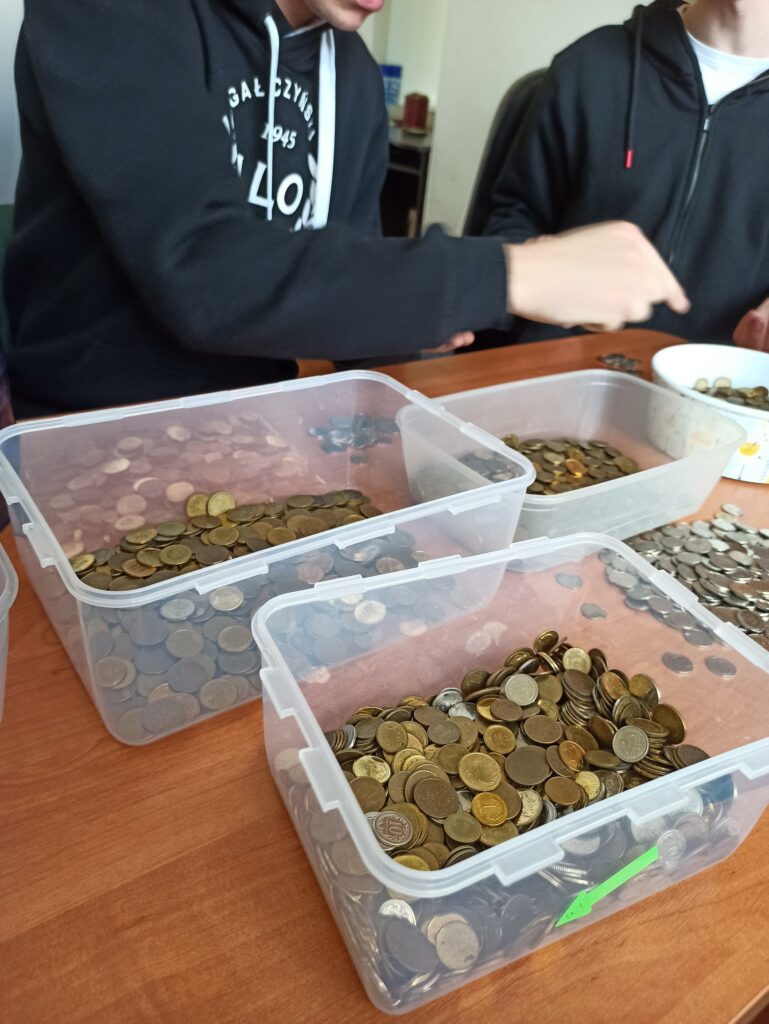 Uczniowie liczą monety zebrane w czasie akcji