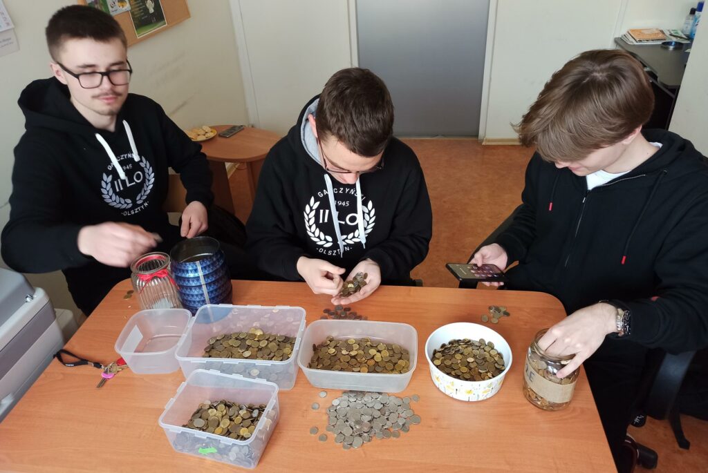 Uczniowie liczą monety zebrane w czasie akcji