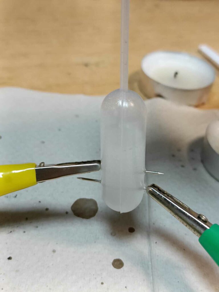 Pipeta, w której znajduje się roztwór - znajdują się w nim widoczne pęcherzyki gazu - wodoru i tlenu